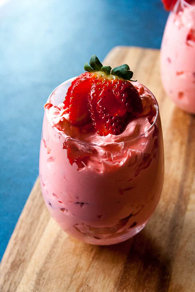 Strawberry Fluff in a glass, topped with a fresh berry.
