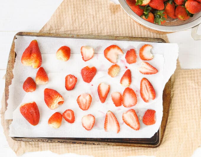 Fresh berries with leaves removed on paper towels on a baking sheet.