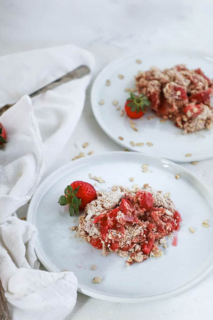 Strawberry Crisp on a white plate with a whole strawberry.