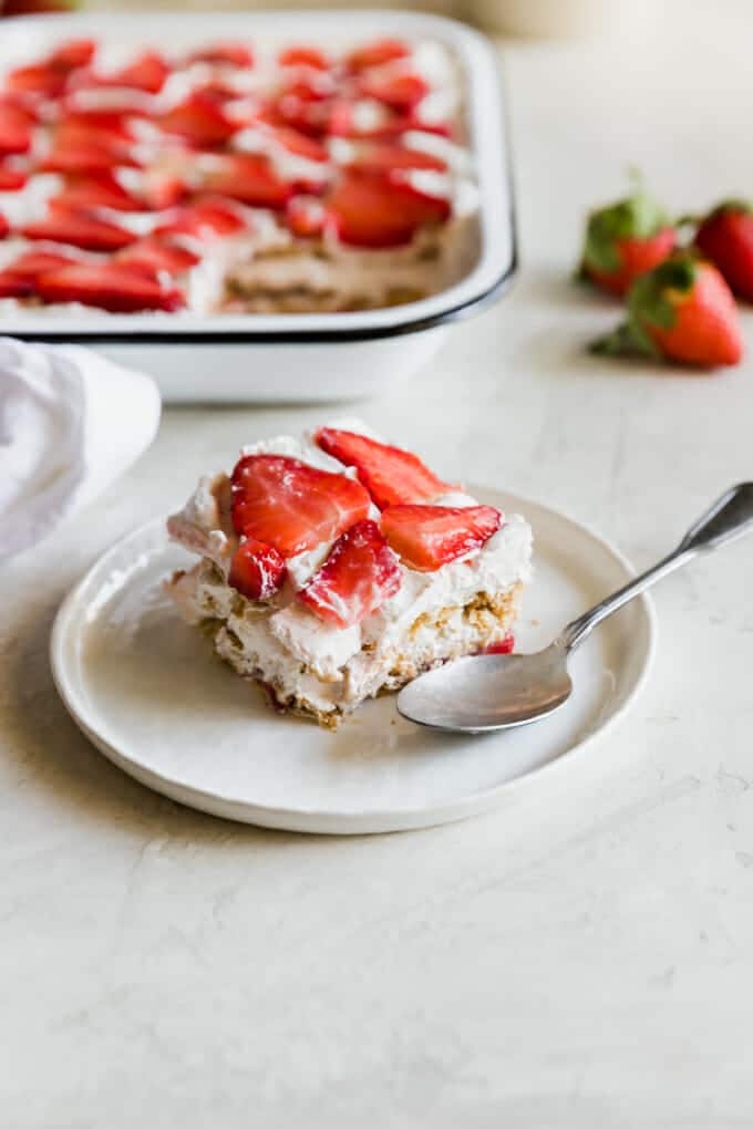 Strawberry cake on a white plate with a spoon.