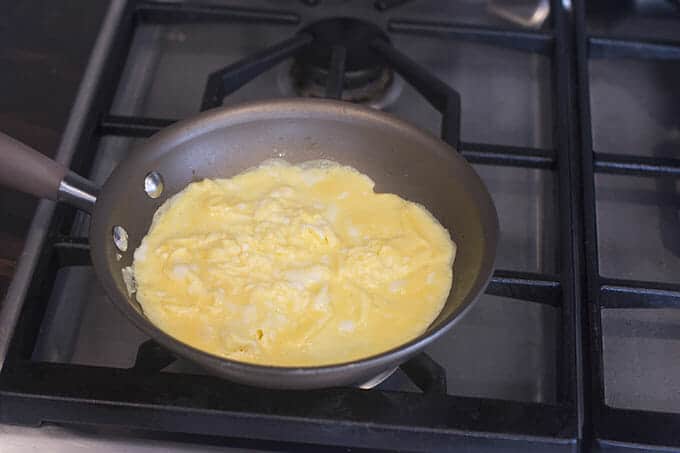 Partially cooked eggs in a pan on the stove.