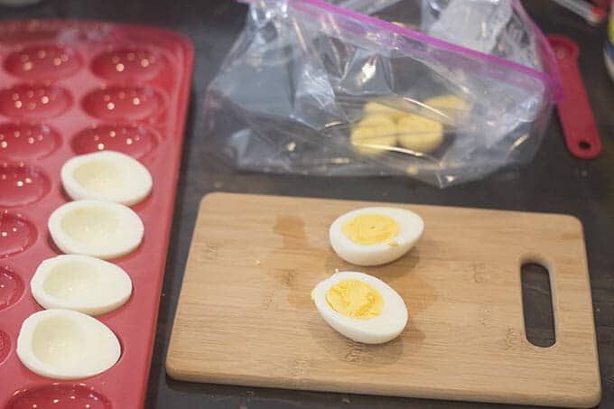 Deviled eggs cut in half with the yolks being removed.