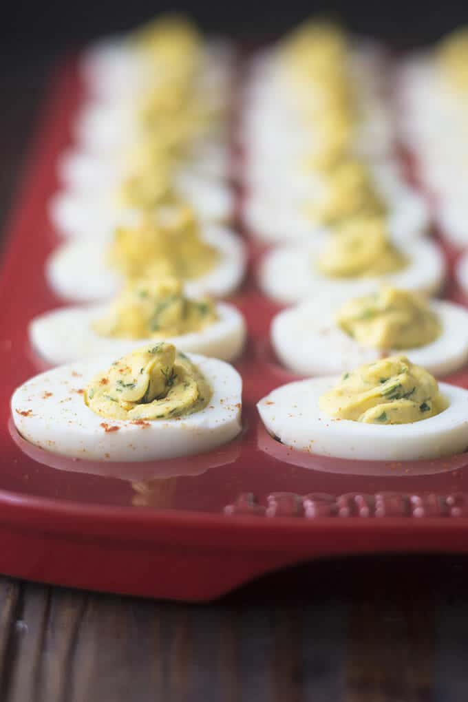 Deviled eggs in a dark red serving tray.