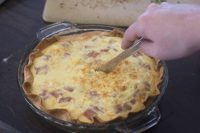 Quiche being cut with a knife.