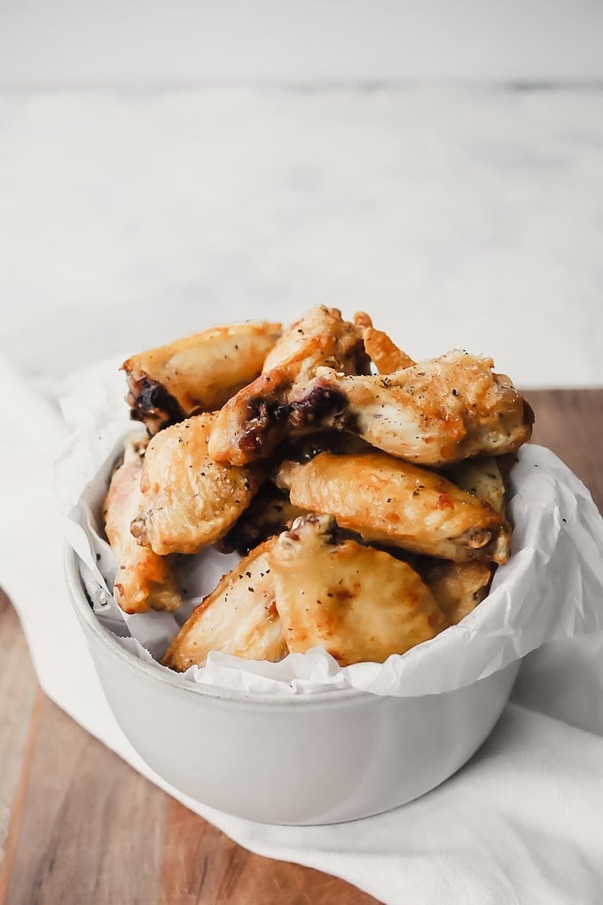 Chicken wings in a white bowl with parchment paper.