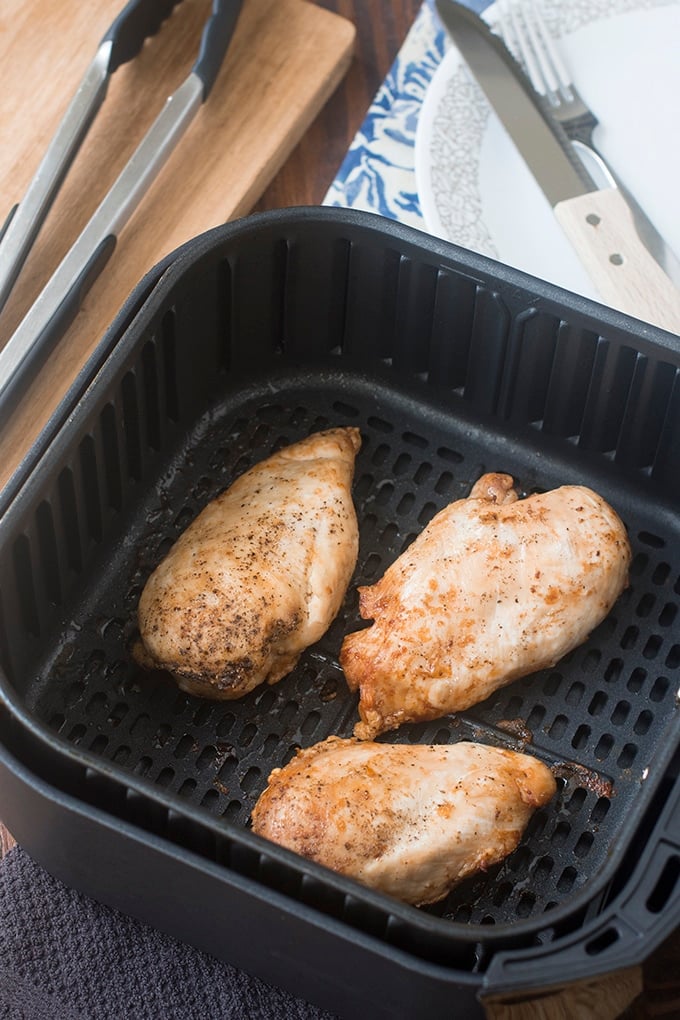 Chicken breasts in an air fryer basket.