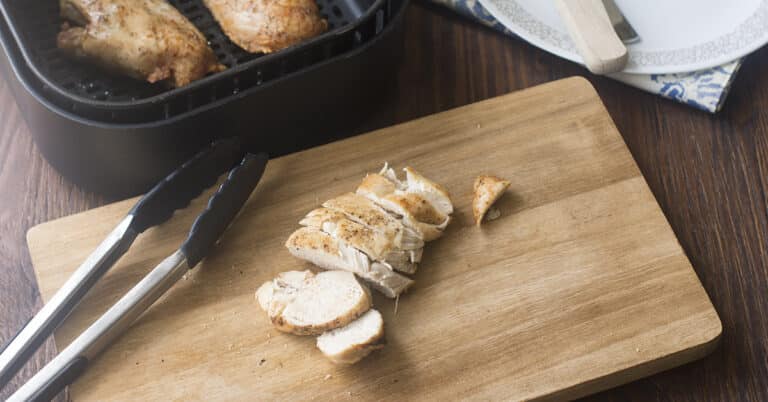 Chicken breasts in an air fryer basket.