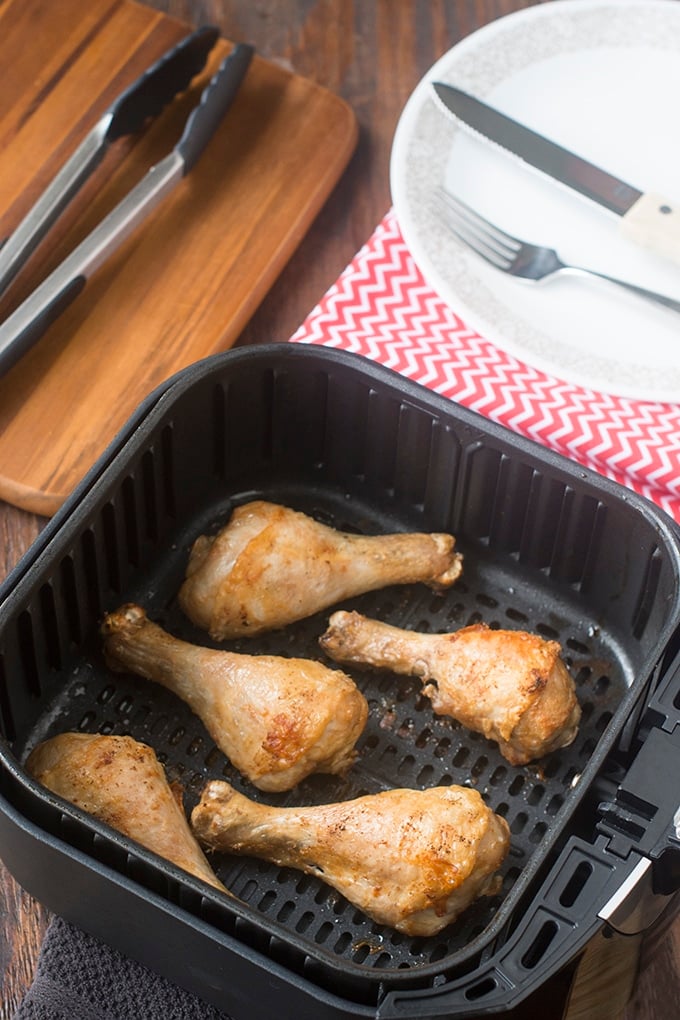 Cooked chicken drumsticks in the air fryer basket.