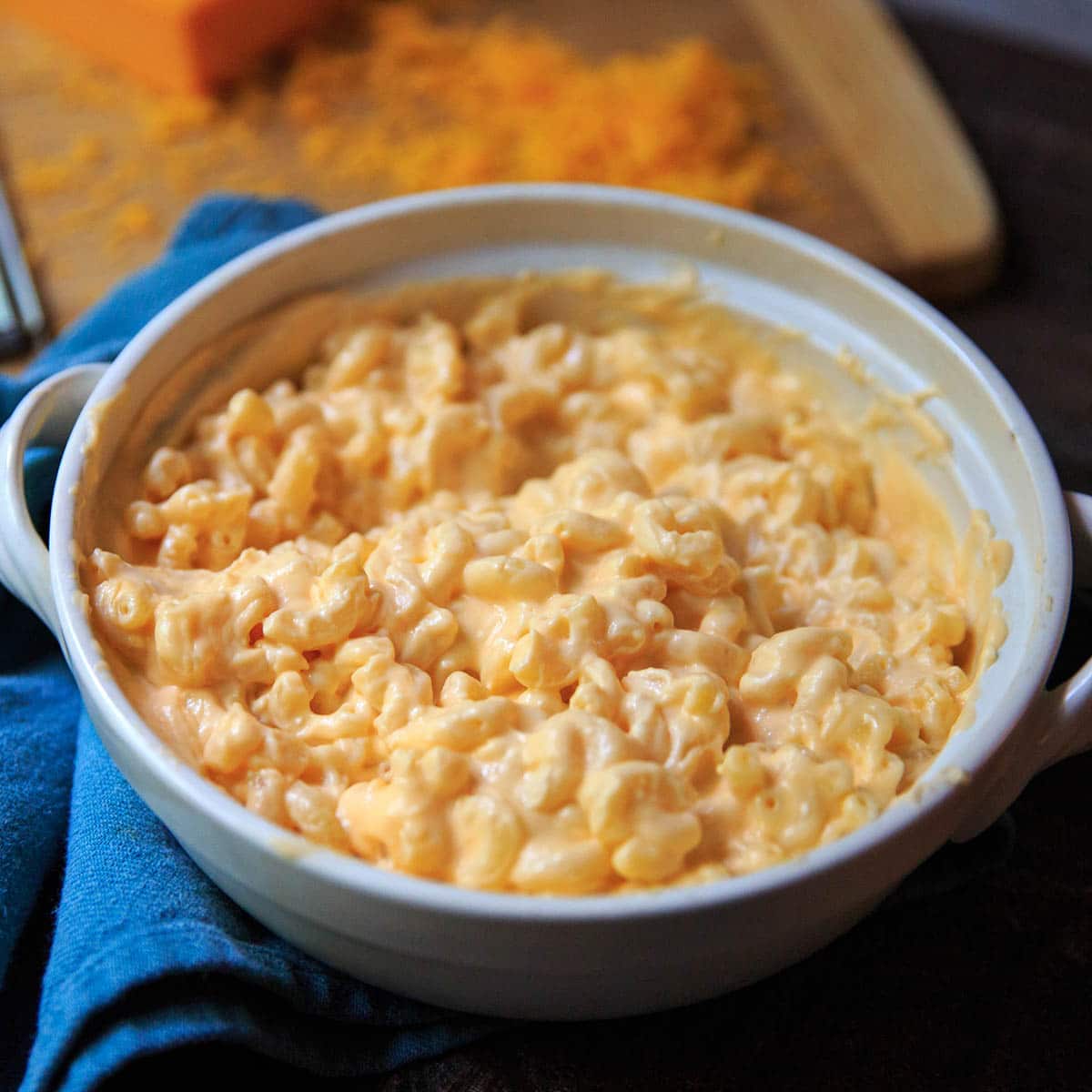 Serving dish of creamiest mac and cheese with grated cheddar in background.