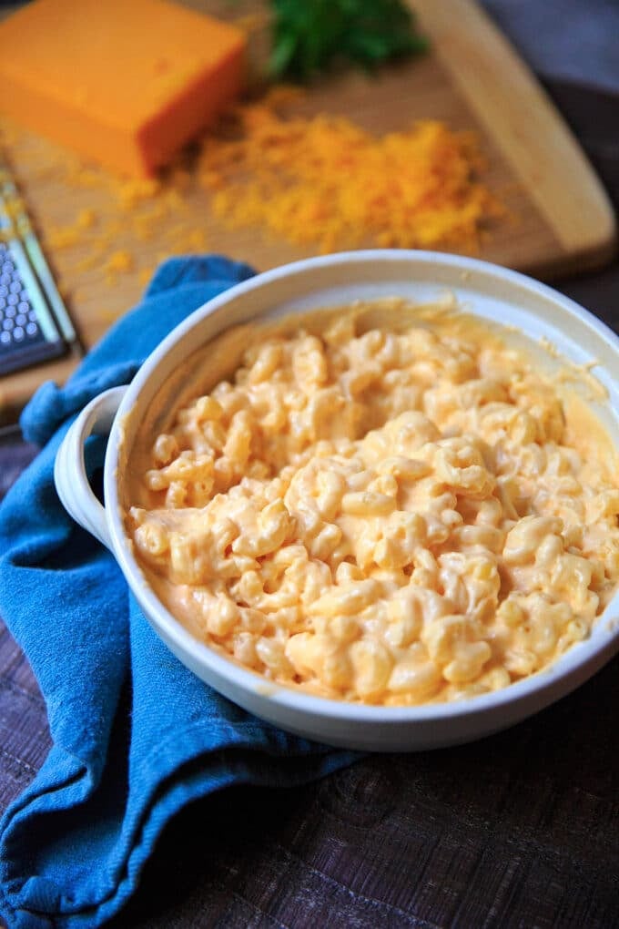 Serving dish of creamiest mac and cheese with grated cheddar in background.