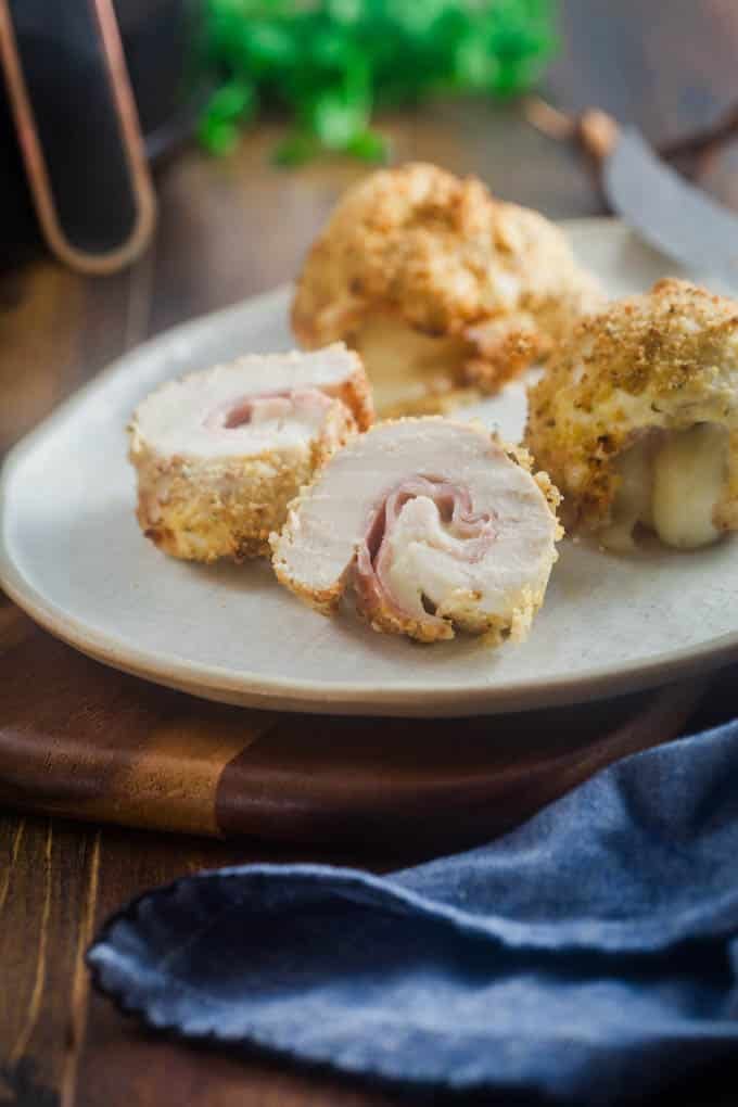 You're going to love Chicken Cordon Bleu in the air fryer. It cooks faster and turns out perfectly crispy. Sliced chicken cordon blue on a white plate.