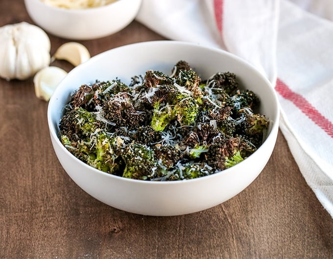 White bowl of air fried broccoli with Parmesan.