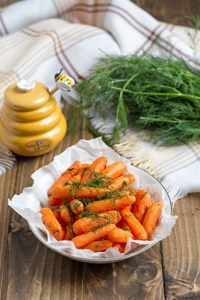 Baby carrots with glaze and herbs in a bowl.