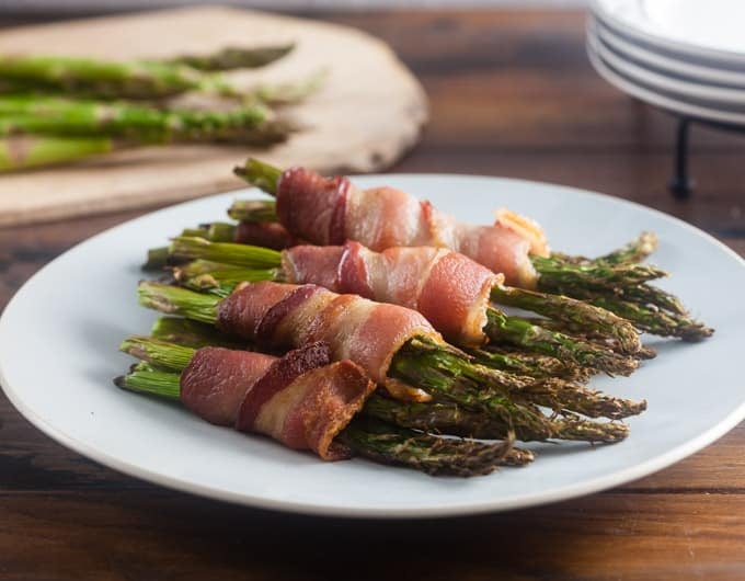 White plate with pile of bacon wrapped asparagus