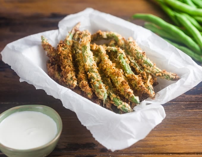 Green bean fries in a parchment paper lined basket.