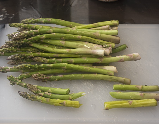 Trimming stems off of raw asparagus.