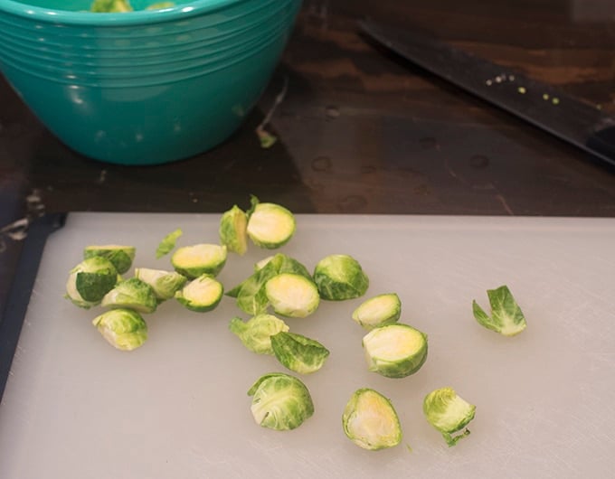 Halved brussels sprouts on a plastic cutting board.