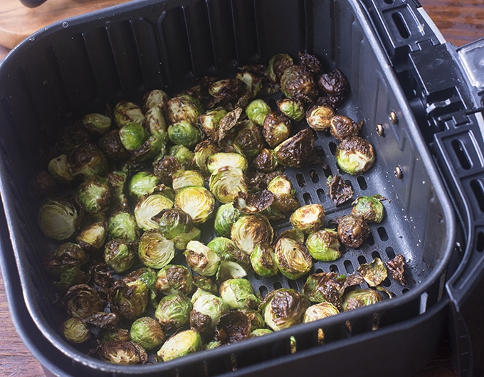 Cooked brussels sprouts in air fryer basket.