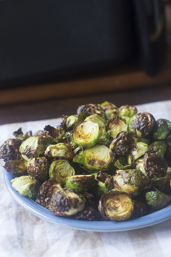 Roasted halved brussels sprouts on a blue plate.
