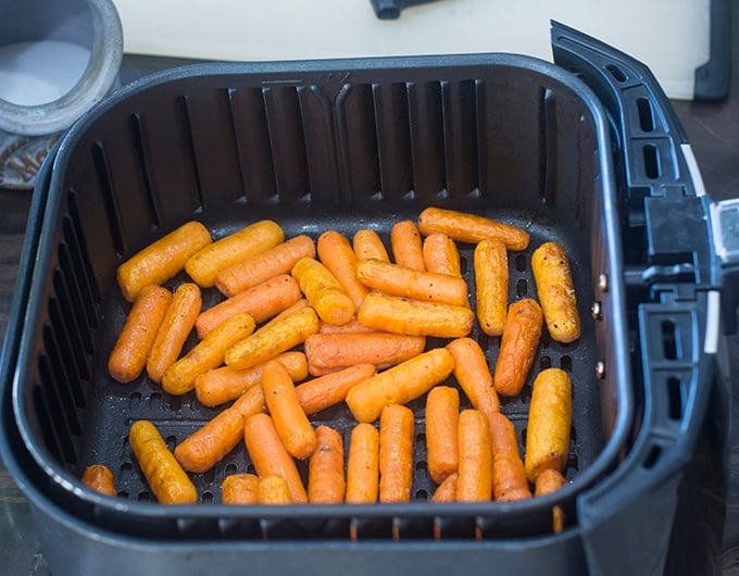 cooked baby carrots in the air fryer basket.
