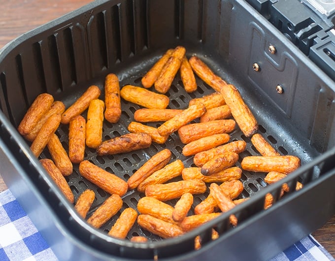 Well browned baby carrots in air fryer basket.