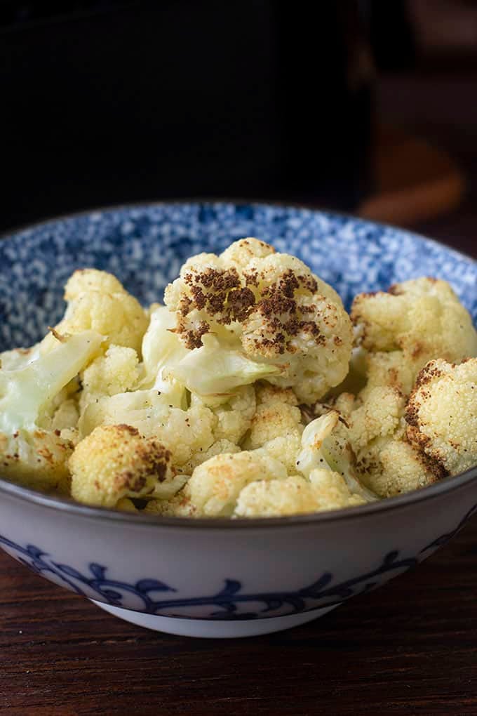 Cooked cauliflower in a blue and white bowl.