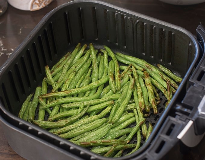 Cooked green beans in air fryer basket.