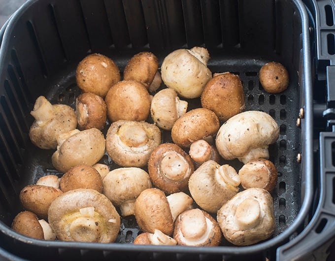 Uncooked mushrooms in air fryer basket.