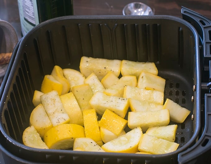 Raw yellow squash in the air fryer basket.