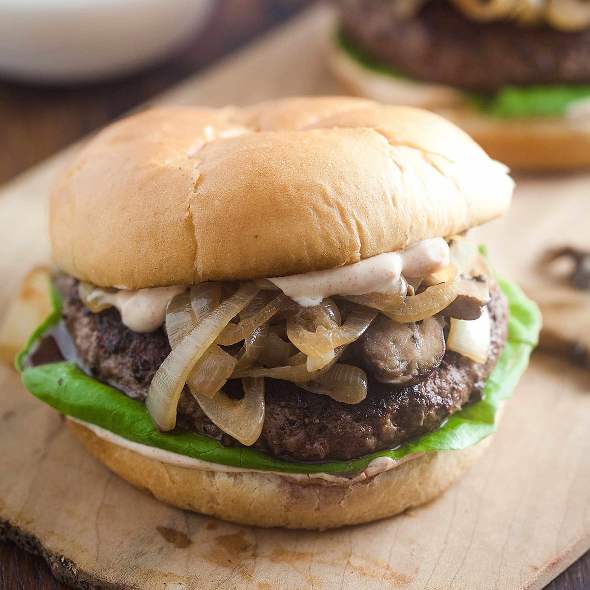 A burger with mushrooms and onions and lettuce on it.
