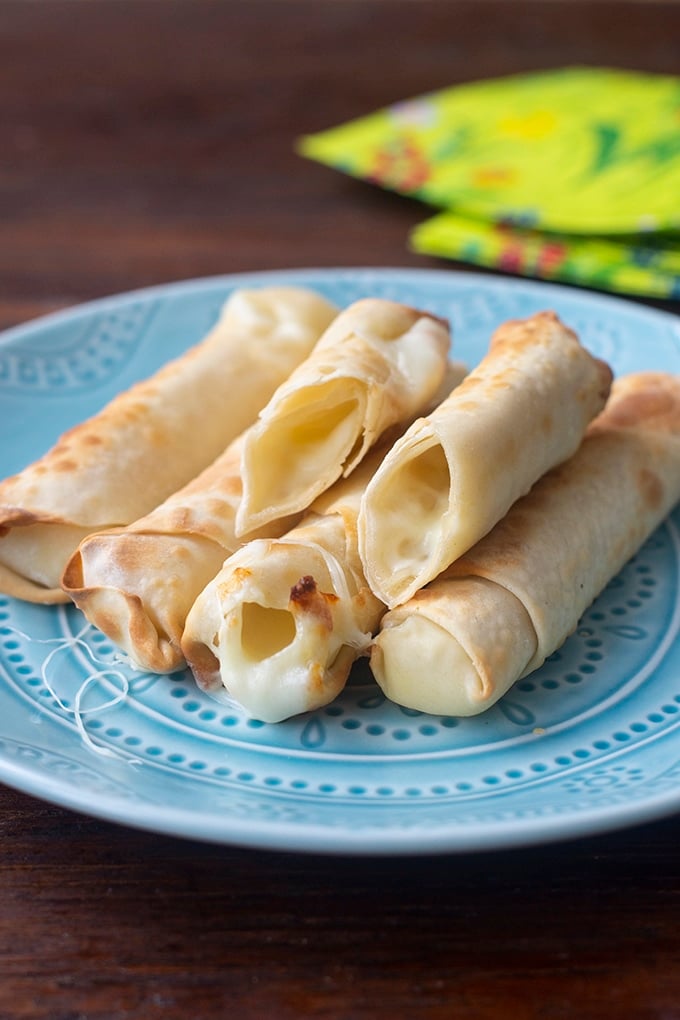 mozzarella sticks on light blue plate; bright yellow cloth with red flowers and green leaves