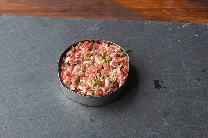 Beef tartare mixture in round cookie cutter.