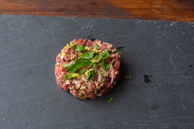 Beef tartare topped with parsley and lemon zest.