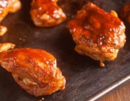 chicken thighs with bbq sauce on them on sheet pan