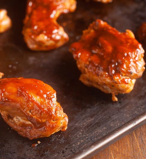 chicken thighs with bbq sauce on them on sheet pan