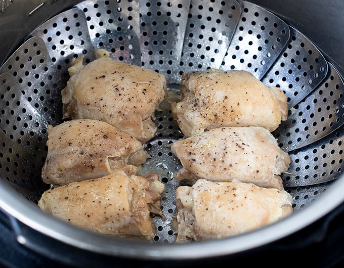 6 chicken thighs with black pepper on them in stainless steel steamer basket
