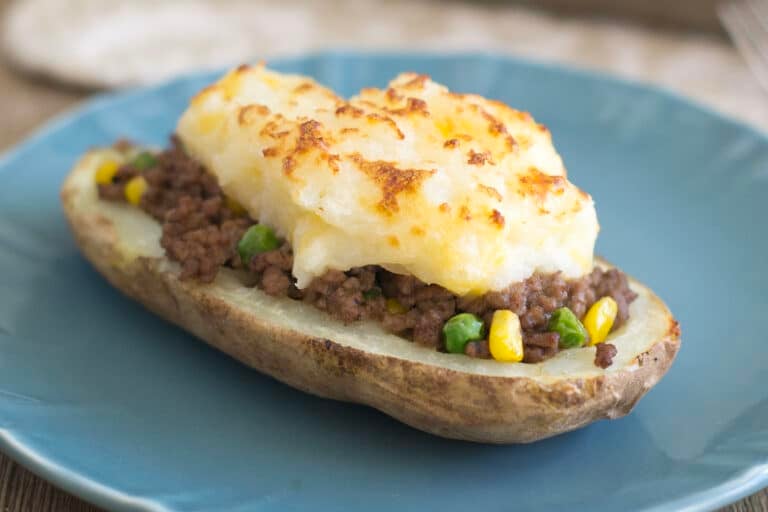 A half of a potato filled with a ground beef and veggie mixture and topped with broiled mashed potatoes