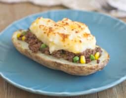 A half of a potato filled with a ground beef and veggie mixture and topped with broiled mashed potatoes