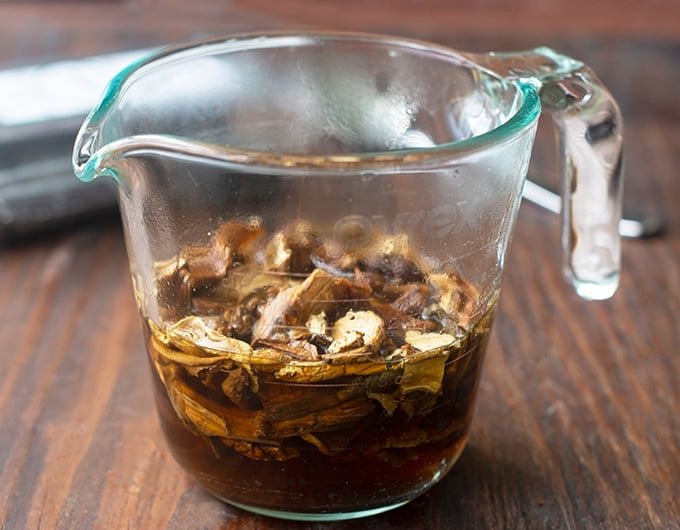 measuring cup with dried mushrooms soaking in water in it