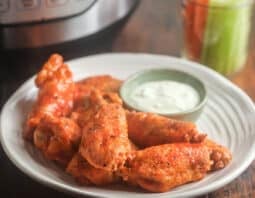 Buffalo chicken wings on a plate with ranch. in front of Instant Pot.