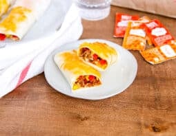 2 grilled cheese burrito on white plates with taco bell plater and sauce packets in background