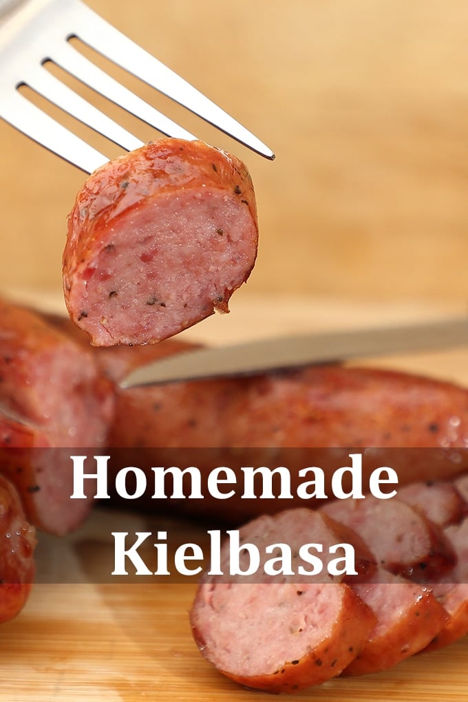 Slices of kielbasa on a wooden surface. One slice is held up on a fork. The words "Homemade Kielbasa" are on the image.