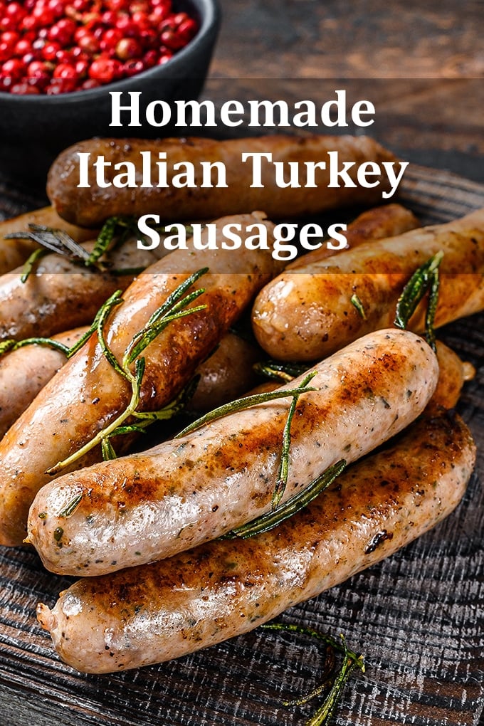 Cooked turkey sausage links on a wooden table with herbs scattered over top and a bowl of berries in the background. The words "Homemade Italian Turkey Sausages" appear on the image.