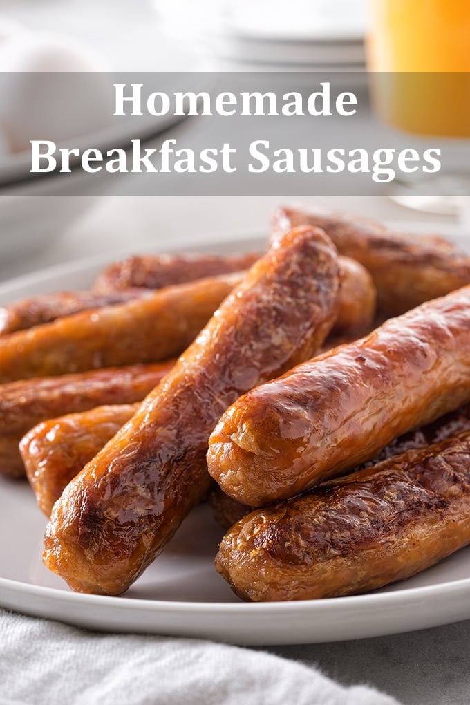 Cooked breakfast sausage links in a pile on a white plate with a glass of orange juice in the background. The words "Homemade Breakfast Sausages" appears on the image.