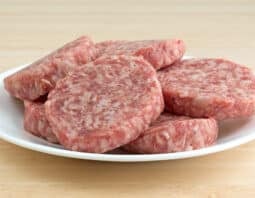 Raw breakfast sausage patties on a white plate