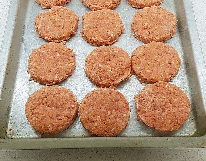 Uncooked sausage patties on a sheet pan