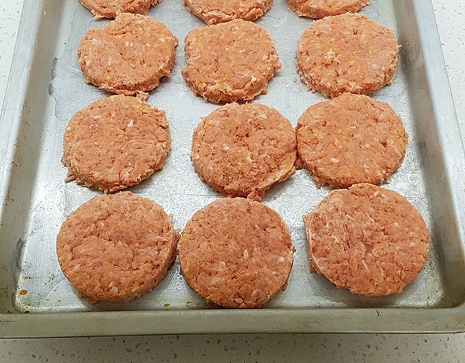 Uncooked sausage patties on a sheet pan