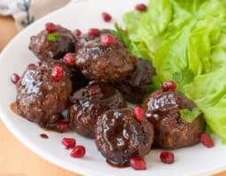 lamb meatballs garnished with pomegranate arils; lettuce served on the side