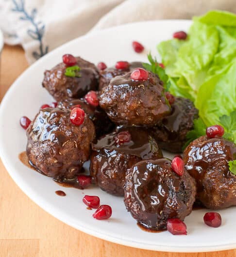 lamb meatballs garnished with pomegranate arils; lettuce served on the side