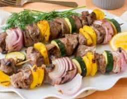 skewers with lamb, red onion, and yellow bell pepper on them